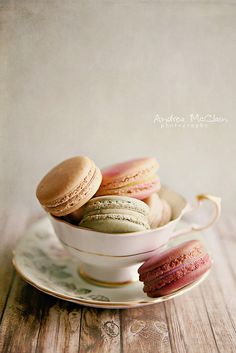 a bowl filled with colorful macaroons on top of a wooden table