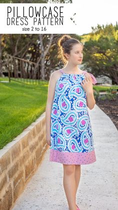 a girl in a blue and pink dress walking down a sidewalk with her hand on her hip