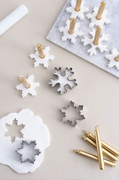 snowflakes and other holiday decorations on a white table with gold pins in the middle