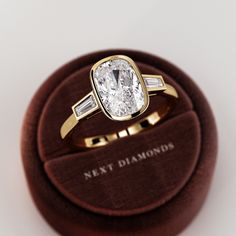 a diamond ring sitting on top of a velvet case in a wooden display box that says next diamonds