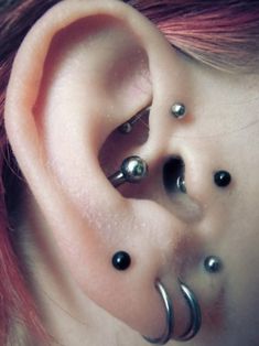 a woman with red hair has three piercings on her ear and one is black