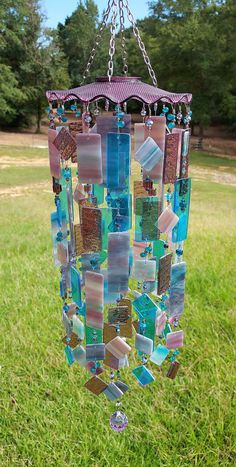 a wind chime hanging from a chain in the grass