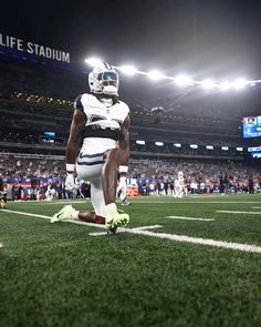 a football player sitting on the field at night with his feet in the air,