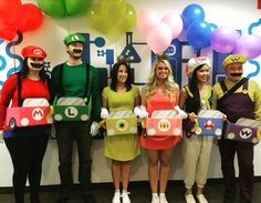 some people are dressed up as mario and luigi in front of a wall with balloons