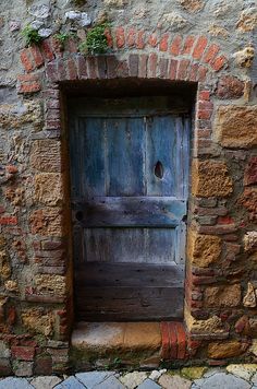 an old wooden door is open on a brick wall