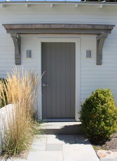 a white building with a gray door and some plants