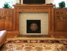 a living room with a fire place in the center and a television mounted above it