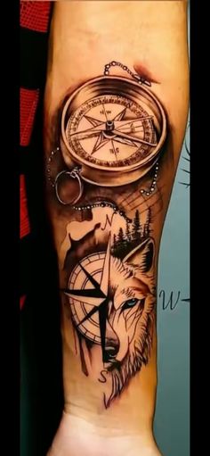 a man's arm with a compass and a wolf tattoo on the left side