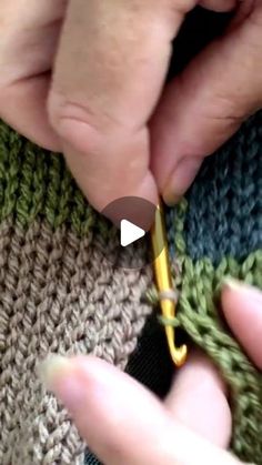 someone is crocheting the side of a green and gray sweater with a yellow needle