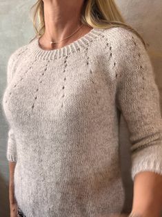 a woman with blonde hair wearing a gray sweater