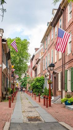 an american flag is flying in the wind on a brick street lined with red, white and blue buildings