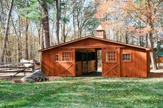 a small wooden shed in the middle of a forest with trees and grass around it