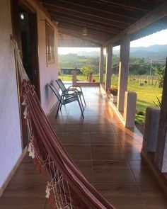 a hammock hanging from the side of a house next to a patio with chairs