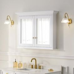 a white bathroom with gold fixtures on the vanity and mirror above it, along with two sinks