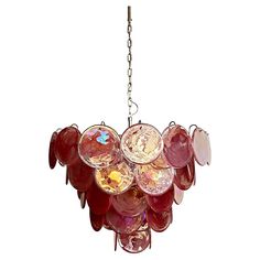 a red chandelier hanging from a chain on a white background with lots of glass discs