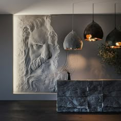 a room with some lights hanging from the ceiling and a stone sculpture on the wall