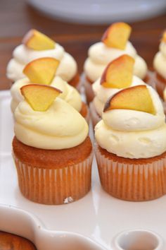 cupcakes with white frosting and apple slices on top are sitting on a plate