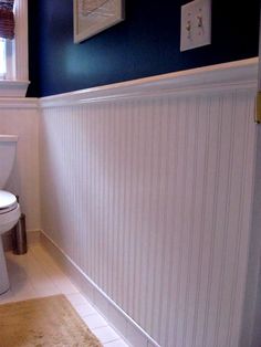 a white toilet sitting in a bathroom next to a window with blue paint on the walls