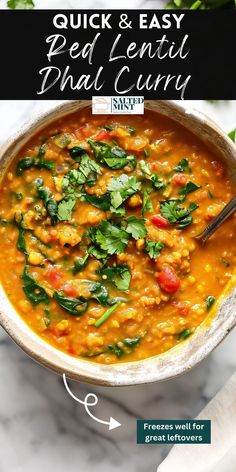 a white bowl filled with red lentula and spinach soup next to a green leafy garnish