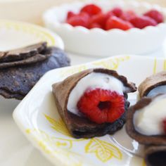 three desserts with raspberries and cream on them sitting on a yellow and white plate