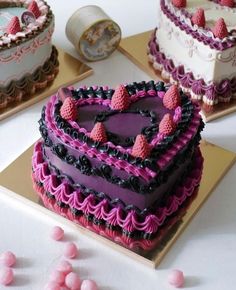 three heart shaped cakes sitting on top of a table next to pink and purple candies