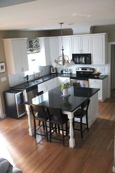 a kitchen with white cabinets and black counter tops