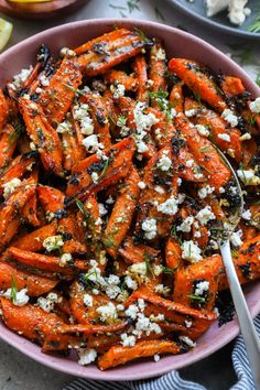 a bowl filled with carrots and feta cheese on top of a white table cloth