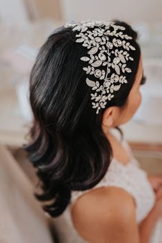 a woman wearing a bridal hair comb with flowers on it's head and pearls in her hair