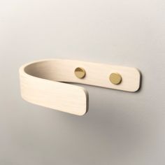 a pair of brass - plated hooks hang on a white wall