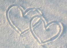 two hearts drawn in the snow on a sunny day