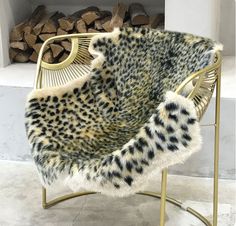 a leopard print chair sitting next to a fire place with logs in the fireplace behind it