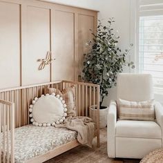 a baby's room with a crib, rocking chair and potted plant