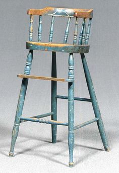 an old wooden chair with blue paint on the back and seat, sitting in front of a gray background