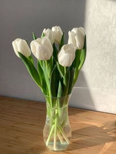 a vase filled with white flowers on top of a wooden table