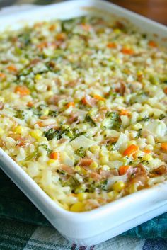 a casserole dish with broccoli, carrots and other toppings