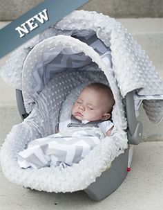 a baby sleeping in a car seat on the sidewalk next to a sign that says new