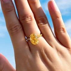 a woman's hand with a yellow diamond ring on top of her left hand