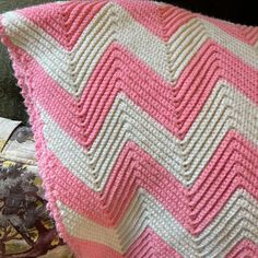 a pink and white crocheted pillow sitting on top of a couch next to a plant