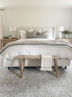 a white bed with two wooden benches in front of it