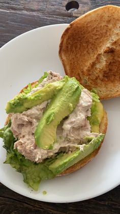 a sandwich with meat and lettuce on a white plate next to a piece of bread