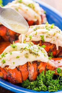 someone is dipping sauce on some lobsters in a blue bowl with parsley and parsley