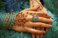 a woman's hands with henna tattoos and bracelets