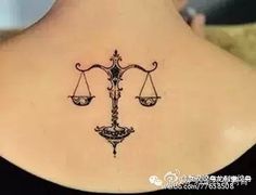 the back of a woman's neck with a libra symbol tattoo on it