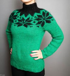 a woman is wearing a green sweater with black flowers on it and has her hands on her hips