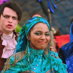 two people dressed in costumes standing next to each other and one person with blue hair