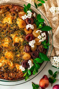 an image of a pie with flowers and herbs around it on a tablecloth next to other food items