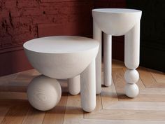 two white stools sitting on top of a hard wood floor next to a brick wall