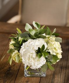 a vase filled with white flowers on top of a wooden table