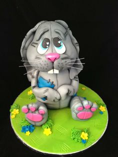 a cake with a cat on top of it and flowers around the edges that are green