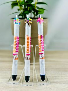 three pens sitting on top of each other in front of a potted plant